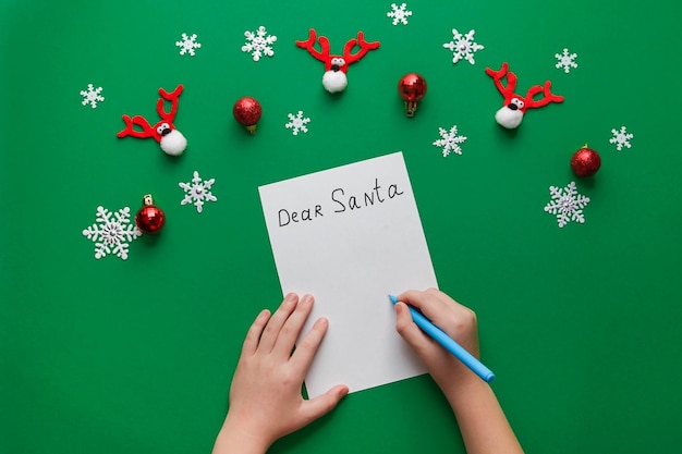 Le mani dei bambini scrivono una lettera a Babbo Natale su un pezzo di carta artigianale Vista dall'alto Spazio per la copia del mockup per il testo