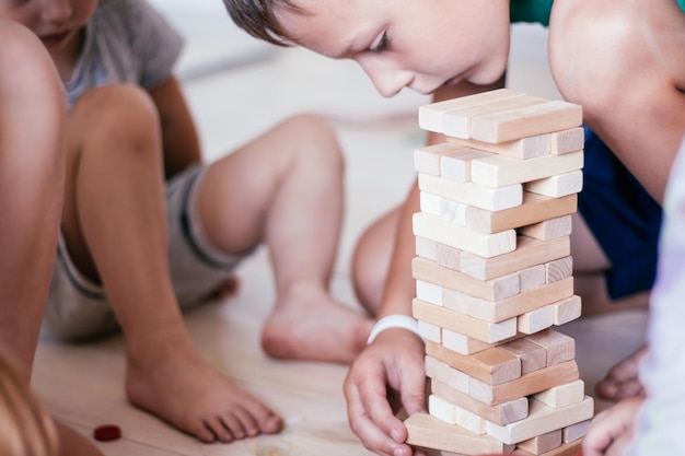 Le mani dei bambini sfocate giocano con la torre, fatta di blocchi di legno