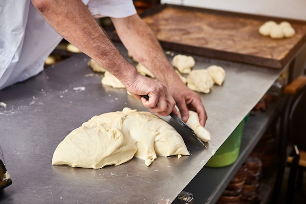 Le mani dei fornai formano l'impasto per la cottura del pane e lo mettono nella teglia al momento della produzione