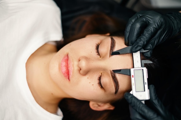 Le mani dei maestri di bellezza eseguono il trucco permanente delle sopracciglia Traumi minimi alla pelle Il microblading delle sopracciglia viene eseguito utilizzando l'impugnatura del manipolatore e un ugello speciale con aghi Livello di abilità del cosmetologo