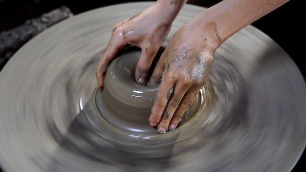 Le mani dei vasai stanno creando un vaso o un vaso di terracotta su ruota