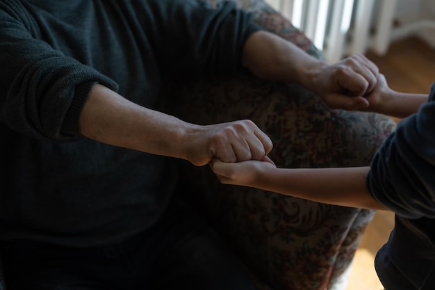 le mani del bambino che abbracciano una mano del vecchio.