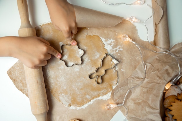 Le mani del bambino fanno i biscotti sull'impasto con uno stampo