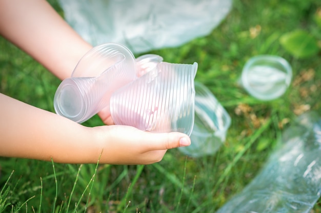 Le mani del bambino puliscono il parco dagli utensili di plastica usati nell'erba