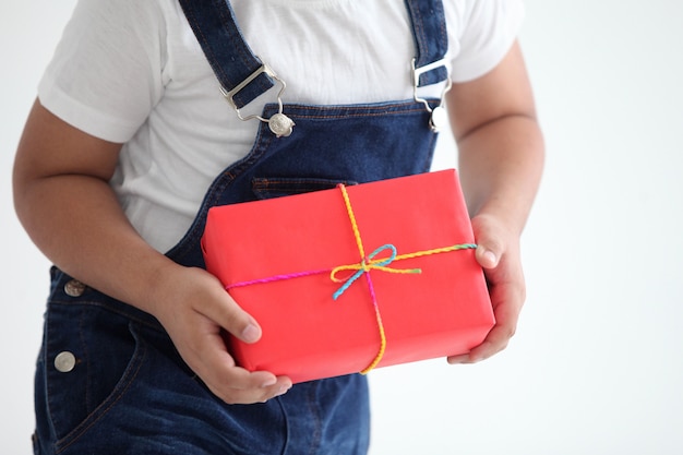 Le mani del bambino tengono il contenitore di regalo rosso