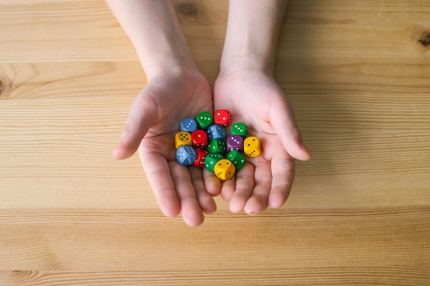 Le mani del bambino tengono molti dadi da gioco multicolori