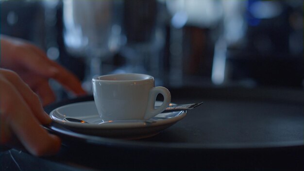 Le mani del barista danno una tazza di caffè fresco al primo piano del cameriere La persona ha fatto bere