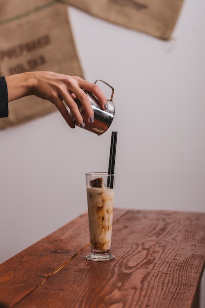 Le mani del barista sta versando il latte che fa il caffè