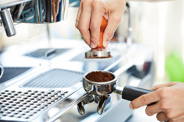 Le mani del barista temperano il caffè sullo sfondo di una macchina da caffè