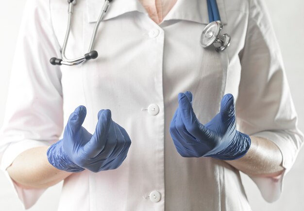 Le mani del dottore in guanti blu si chiudono per spiegare e raccontare smth. Medico specialista, medico in uniforme con stetoscopio durante la consultazione professionale.