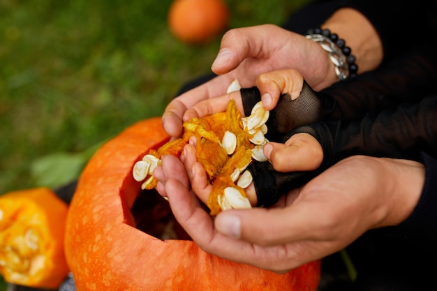 Le mani del padre e della figlia estraggono semi e materiale fibroso da una zucca prima di scolpire per Halloween. Vista dall'alto, primo piano, vista dall'alto, copia dello spazio