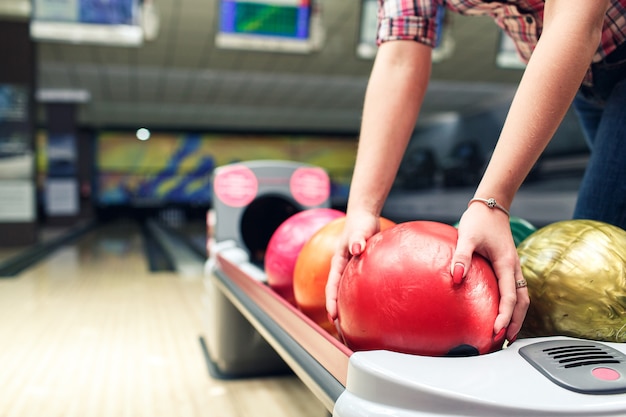 Le mani del primo piano delle ragazze prendono la palla da bowling.