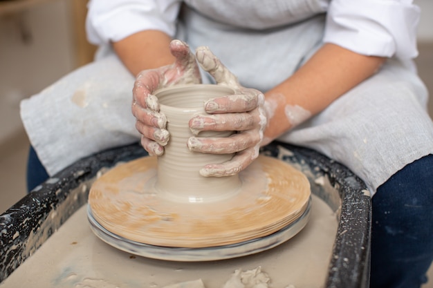 Le mani del vasaio che formano ceramiche dall'argilla sul tornio da vasaio. Produzione artigianale.