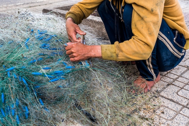 Le mani del vecchio pescatore districano le reti da pesca, Nha Trang