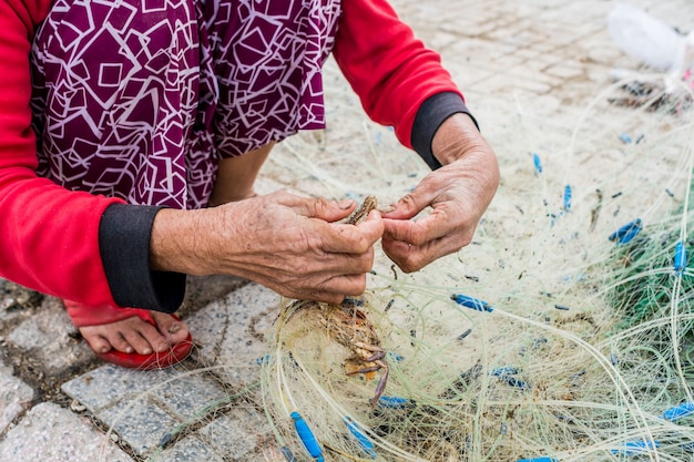 Le mani del vecchio pescatore districano le reti da pesca, Nha Trang