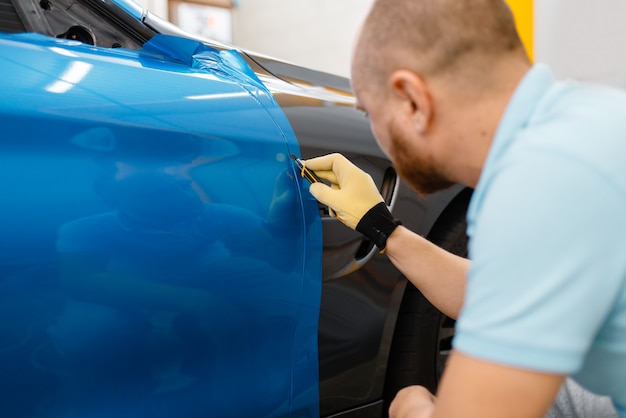 Le mani del wrapper per auto installano un foglio o un film in vinile