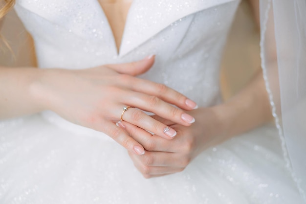 Le mani delicate della sposa in piedi in un abito bianco le mettono un anello nuziale al dito