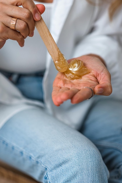 Le mani dell'estetista tengono la pasta di zucchero liquida