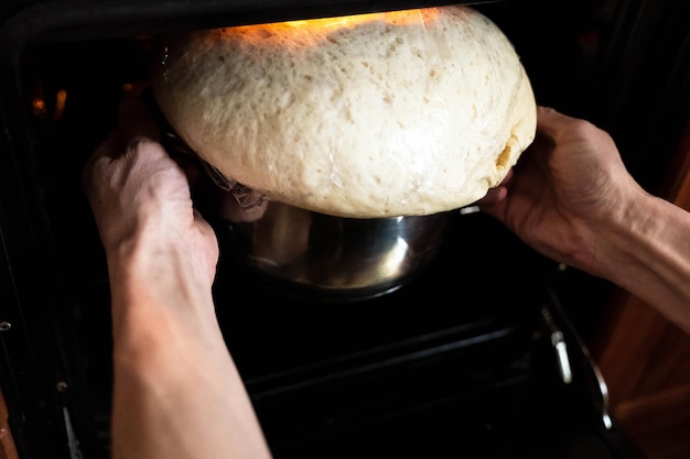 Le mani dell'uomo che impastano l'impasto per il pane nel forno con il lievito e il calore