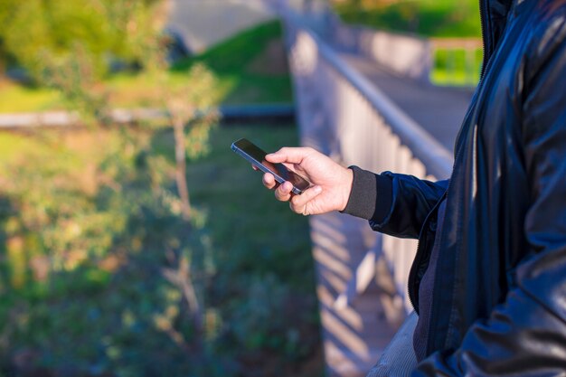 Le mani dell'uomo del primo piano facendo uso del telefono cellulare all'aperto