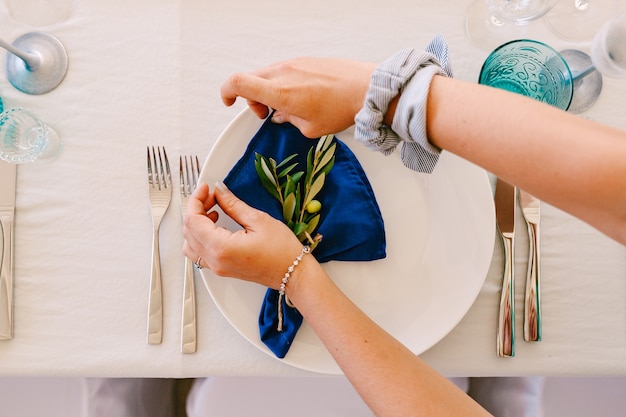 Le mani della donna avvolgono i rami di ulivo che si trovano su un piatto in un tovagliolo