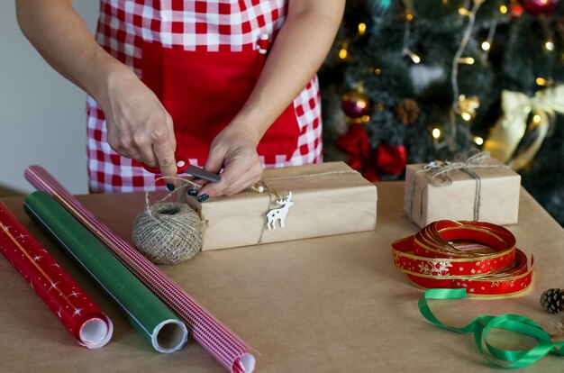 Le mani della donna che confezionano regali di Natale confezionano regali per i regali di Natale e Capodanno