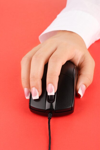 Le mani della donna che spingono i tasti del mouse del pc sul primo piano rosso del fondo