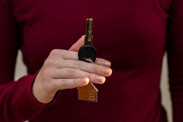 Le mani della donna che tengono la chiave con il portachiavi a forma di casa