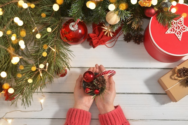 Le mani della donna che tengono la tazza con palloncini rossi, rami di albero di Natale e lecca-lecca Foto autentica