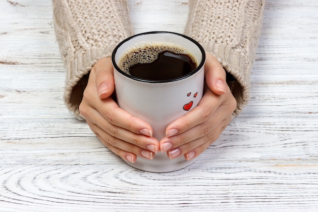 Le mani della donna che tengono tazza con caffè, vista superiore