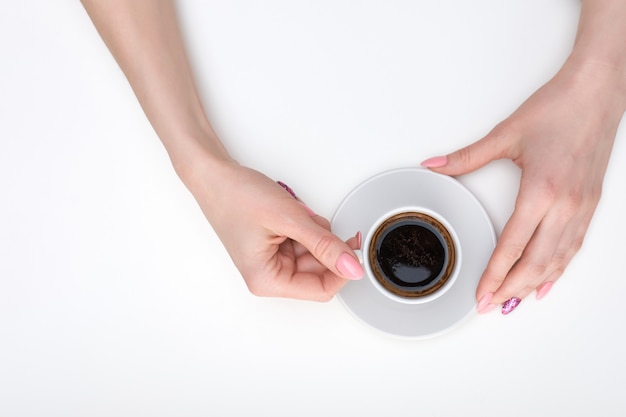 Le mani della donna che tengono tazza di caffè espresso