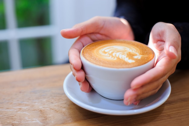 Le mani della donna che tiene tazza con caffè.