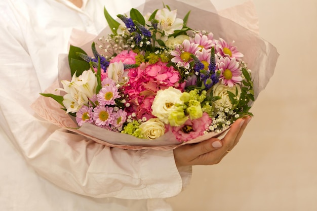 Le mani della donna con enormi fiori di hudrongea viola e rosa su sfondo bianco romantico umore mattutino