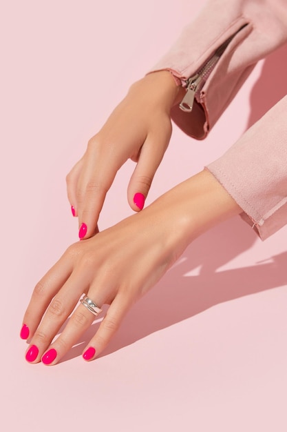 Le mani della donna con il concetto di salone di bellezza pedicure manicure rosa design delle unghie