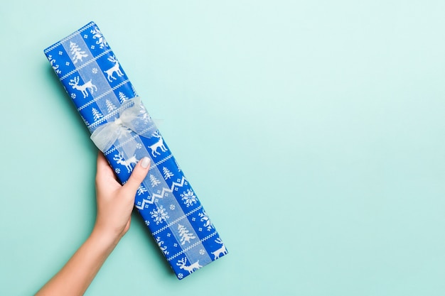 Le mani della donna danno il regalo avvolto del Natale o dell'altra festa fatta a mano in pape colorato