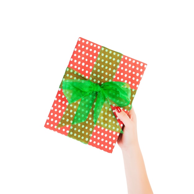 Le mani della donna danno il regalo di Natale avvolto o altra festa fatto a mano in carta rossa con nastro verde. Isolato su sfondo bianco, vista dall'alto. Ringraziamento Confezione regalo concetto.