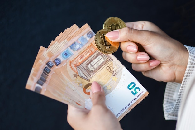 Le mani della donna del primo piano che tengono le monete d'oro della valuta criptata e delle banconote in euro che indossano in giacca bianca Il concetto di risparmio di pagamenti in contanti e stipendi