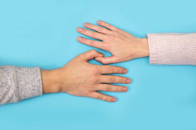 Le mani della donna e dell'uomo tengono la scatola con la fede nuziale sul blu.