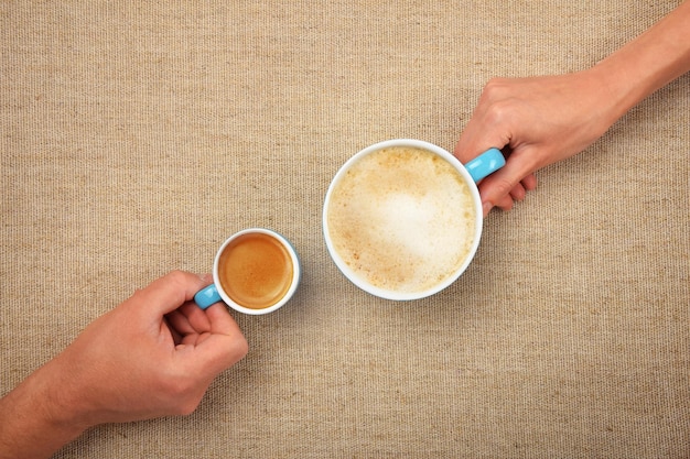 Le mani della donna e dell'uomo tengono le tazze di caffè