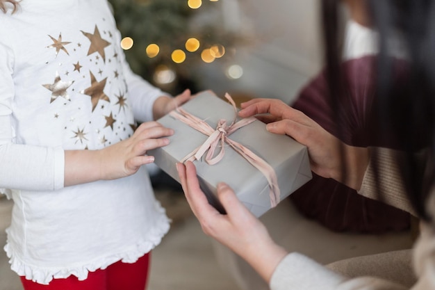 Le mani della donna fanno un regalo a una ragazza La mamma fa un regalo di Natale a sua figlia