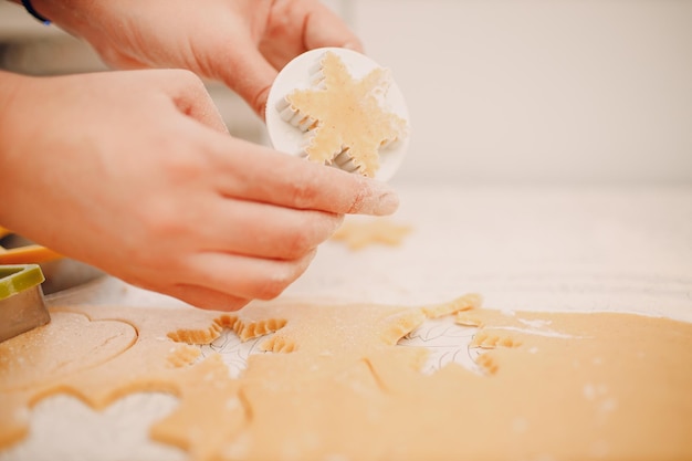 Le mani della donna formano gli stampi, le frese, la pasta allo zenzero e preparano deliziosi biscotti allo zenzero di Natale Cucinare e decorare il dessert di Natale