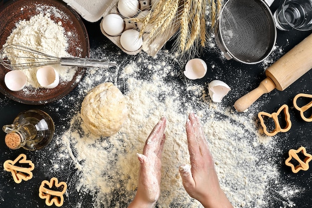 Le mani della donna impastano la pasta sul tavolo con farina uova e ingredienti Vista dall'alto