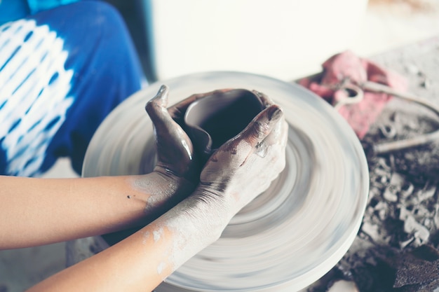 Le mani della donna si chiudono, lo studio magistrale della ceramica lavora con l&#39;argilla su un tornio da vasaio