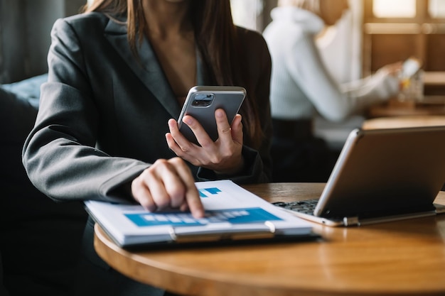 Le mani della donna stanno scrivendo su un laptop e tenendo lo smartphone in ufficio