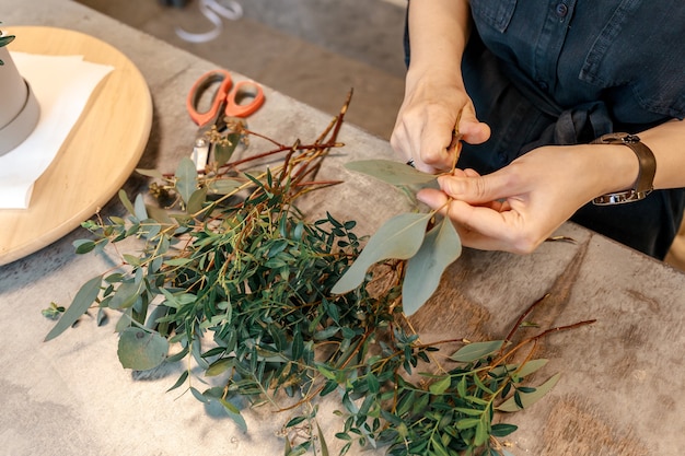 Le mani della donna stanno tagliando le piante, preparandole a creare composizioni floreali in scatola. Concetto di regalo di fiori.