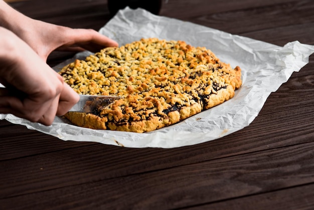 Le mani della donna tagliano la torta di frutta Torta su un tavolo di legno