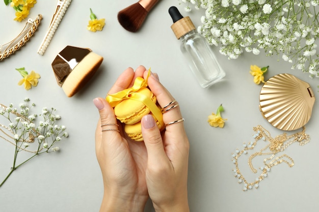 Le mani della donna tengono gli amaretti su sfondo grigio chiaro con accessori femminili