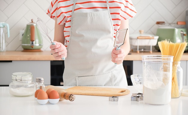 Le mani della donna tengono gli strumenti culinari in cucina