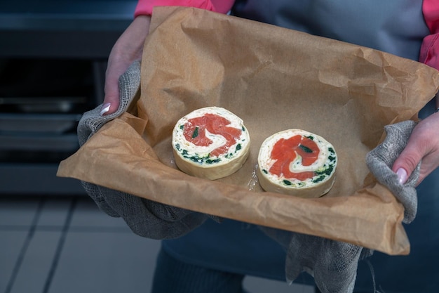 Le mani della donna tengono il rotolo di salmone con il piatto semilavorato di mozzarella