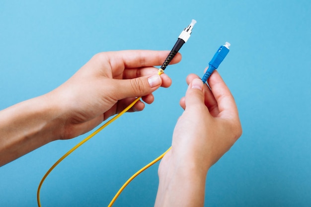 Le mani della donna tengono la modalità singola del cavo patch in fibra ottica del connettore SC e FC su sfondo blu.